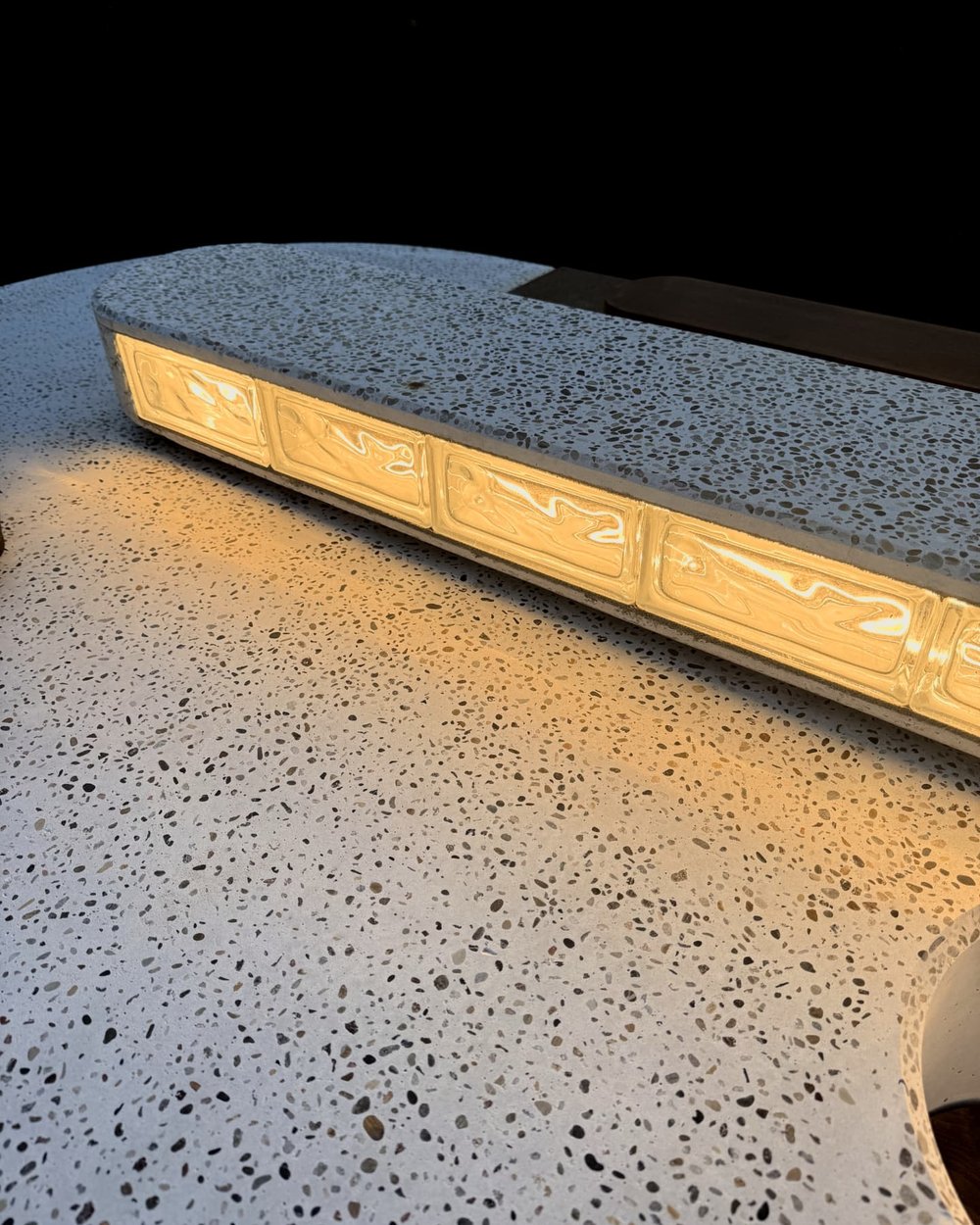 Glass blocks cast into the concrete edge, lit from within after dark