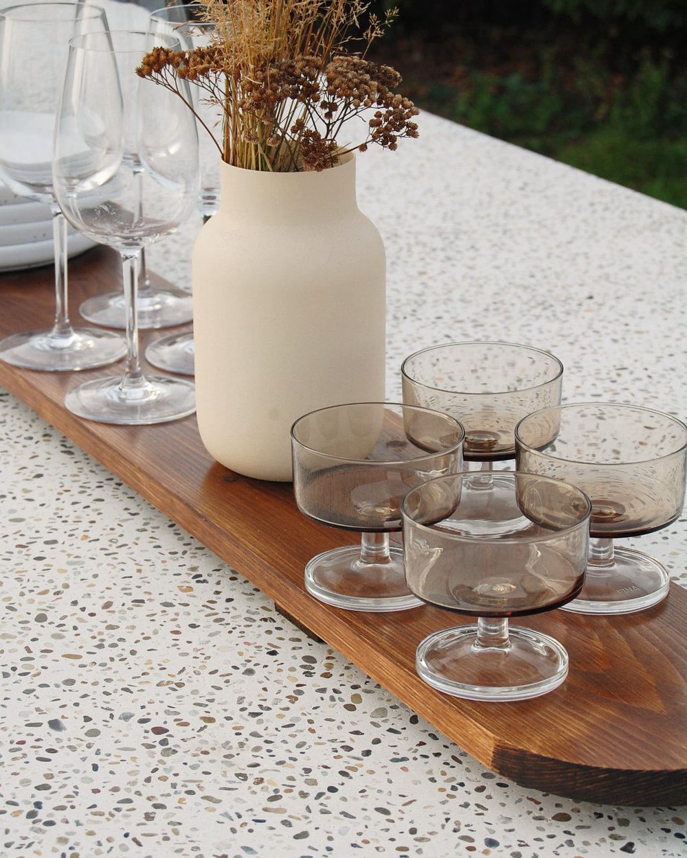 Glasses and a vase on a walnut board resting on the terrazzo top
